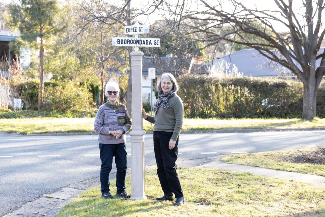 2 older women standing near a heritage street sign in a leafy Inner North Canberra suburb
